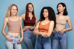 Diverse group multiracial of confident women wearing tank top and jeans looking away blue background photo
