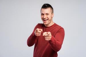 Smiling, happy man pointing his fingers looking at camera, standing isolated on gray background photo