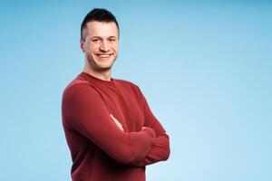 Happy smiling man standing with arms crossed, isolated on blue background photo