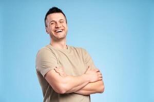 Smiling man in pastel t-shirt with arms crossed, close-up, looking at camera posing in studio photo