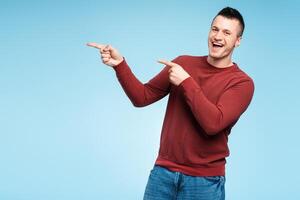 Middle aged smiling man pointing index finger towards copy space for text, logo photo