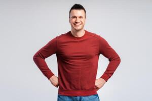 Smiling man in red sweatshirt, looking happy, keeps hands on waist photo