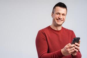 Portrait of smiling middle aged man standing isolated over gray background, using mobile phone photo