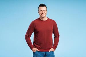 Smiling, middle aged man standing with hands in pockets, wearing casual red sweatshirt photo