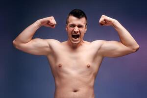 Man showing muscles and screaming with effort on blue background photo