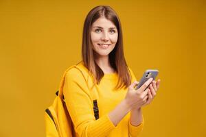Beautiful smiling middle aged woman holding backpack, mobile phone, using mobile app, text message photo