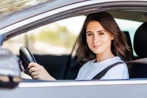 Happy woman driving a car and smiling while enjoying at nature photo