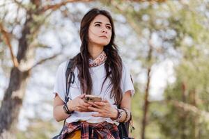 Beautiful woman using mobile application to navigate in autumn forest photo
