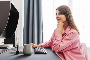 Attractive, smiling woman, freelancer, copywriter working, using computer, typing keyboard photo