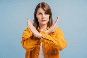 Unhappy middle aged woman showing hands stop gesture looking at camera isolated on blue background photo