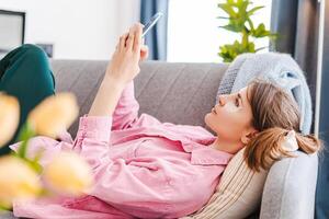 Smiling, middle aged woman with patches under her eyes holding mobile phone, using mobile app photo