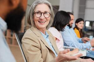 Smiling attractive senior businesswoman smiling during meeting with her team photo