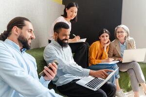 Group of diverse business people having meeting using laptop in modern office photo