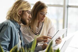Portrait of confident colleagues working together using laptop and digital tablet photo