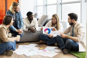 Team of young professionals is brainstorming new project using data visualization on floor in office photo