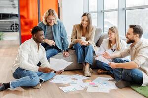 Marketing team having brainstorming session discussing documents on the floor photo