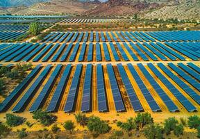 aéreo ver de un desmadejado solar granja con filas de paneles absorbente luz de sol en el Desierto foto