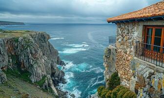 A dramatic cliffside view of the ocean with rugged coastline, seen from a balcony of a cliffside cottage photo