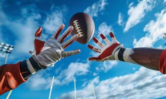 A football player's hands catching the ball mid-air, with the field and goalposts in the background photo