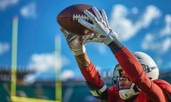 A football player's hands catching the ball mid-air, with the field and goalposts in the background photo