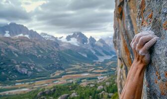 A rock climber's hands gripping a cliff edge, with mountains in the background photo