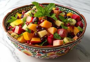 A colorful bowl of mixed fruit salad with exotic fruits and mint leaves photo