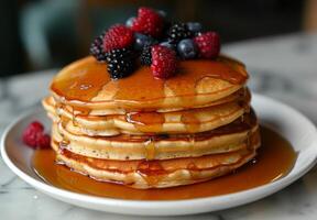 A stack of fluffy pancakes drizzled with maple syrup and topped with fresh berries photo