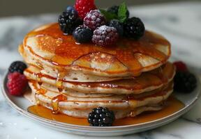 A stack of fluffy pancakes drizzled with maple syrup and topped with fresh berries photo