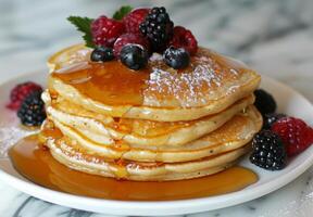 A stack of fluffy pancakes drizzled with maple syrup and topped with fresh berries photo