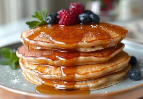 A stack of fluffy pancakes drizzled with maple syrup and topped with fresh berries photo