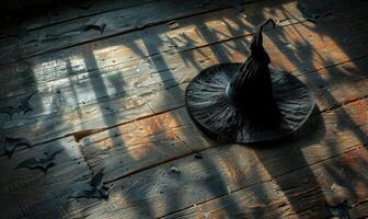 A witch's hat and broomstick lying on a wooden floor with shadows of bats, with plenty of space above for a message photo