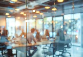 Blurred image of a group of people brainstorming in a glass walled meeting room photo
