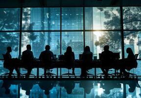 Silhouettes of employees collaborating at a large desk with office equipment photo