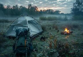 A tent and a fire are in the middle of a field photo