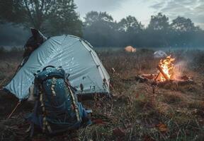A tent and a fire are set up in a field photo