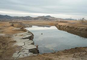 A water hole in the desert with mountains in the background photo