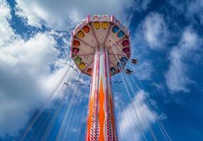 A carnival ride with colorful seats and a blue sky photo