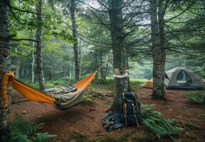 A hammock in the woods with a tent and backpack photo