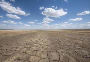 A dry, cracked field with blue sky and clouds photo