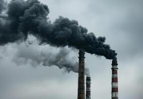 Two chimneys with black smoke coming out of them photo
