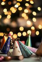 Many party hats are sitting on a table in front of a christmas tree photo