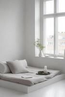 White minimalist bedroom with a low bed, simple decor, and natural light flooding in from a large window photo