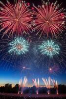 Colorful fireworks lighting up the sky with large bursts, silhouetting a cheering crowd below photo