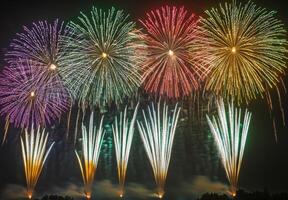 Multiple fireworks of different colors going off simultaneously, lighting up the night with vivid patterns photo
