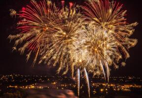 Golden and red fireworks spreading across the sky, with city lights twinkling in the background photo