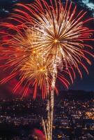 Golden and red fireworks spreading across the sky, with city lights twinkling in the background photo