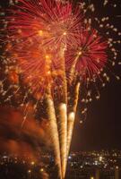Golden and red fireworks spreading across the sky, with city lights twinkling in the background photo