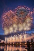 A spectacular finale of fireworks, with layers of colors and light filling the sky over a lake photo