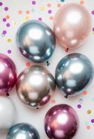 Glossy metallic balloons surrounded by vibrant confetti on a plain background, with plenty of free space for text photo