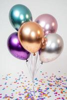 Glossy metallic balloons surrounded by vibrant confetti on a plain background, with plenty of free space for text photo